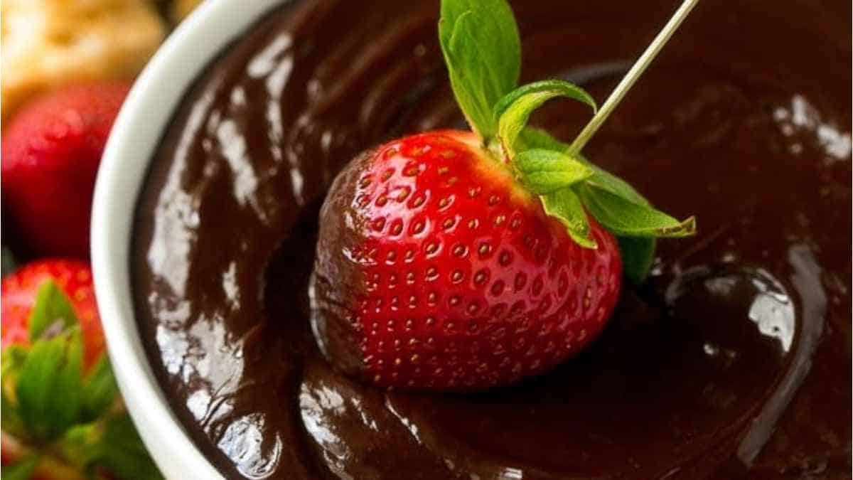 A bowl of chocolate dip with a strawberry on top.