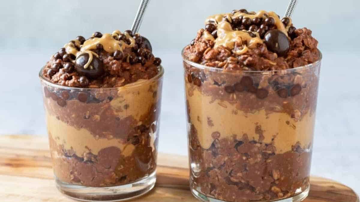 Two glasses filled with chocolate pudding and peanut butter.