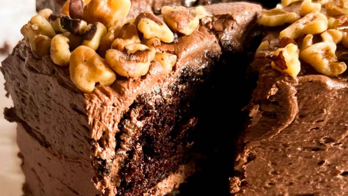 A slice of chocolate cake with walnuts on top.