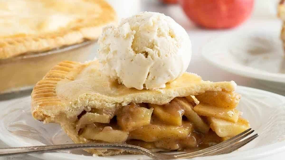 A slice of apple pie with ice cream on a plate.