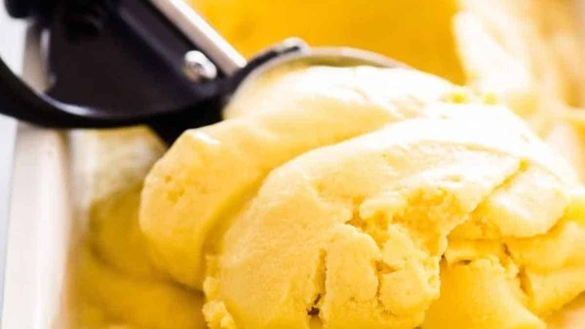 A scoop of yellow ice cream in a white bowl.