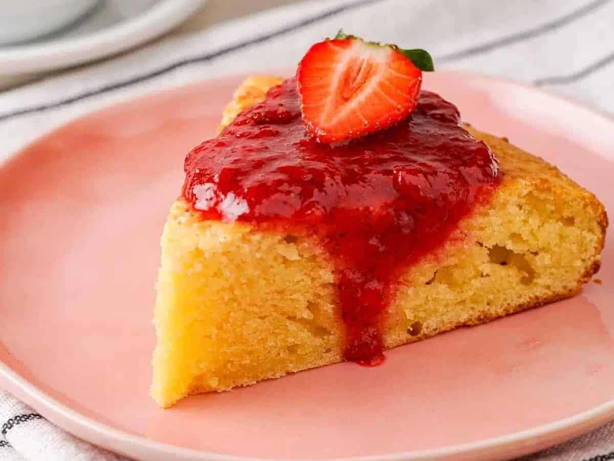 A slice of cake with strawberry sauce on a pink plate.