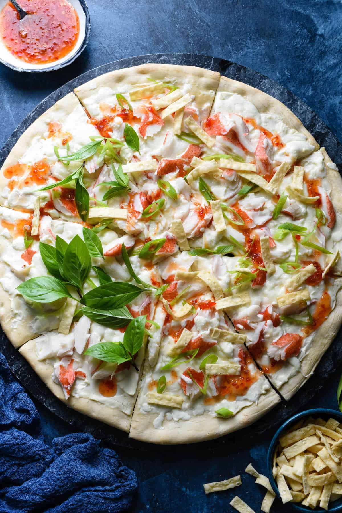 Thai chicken pizza with imitation crab meat on a blue background.