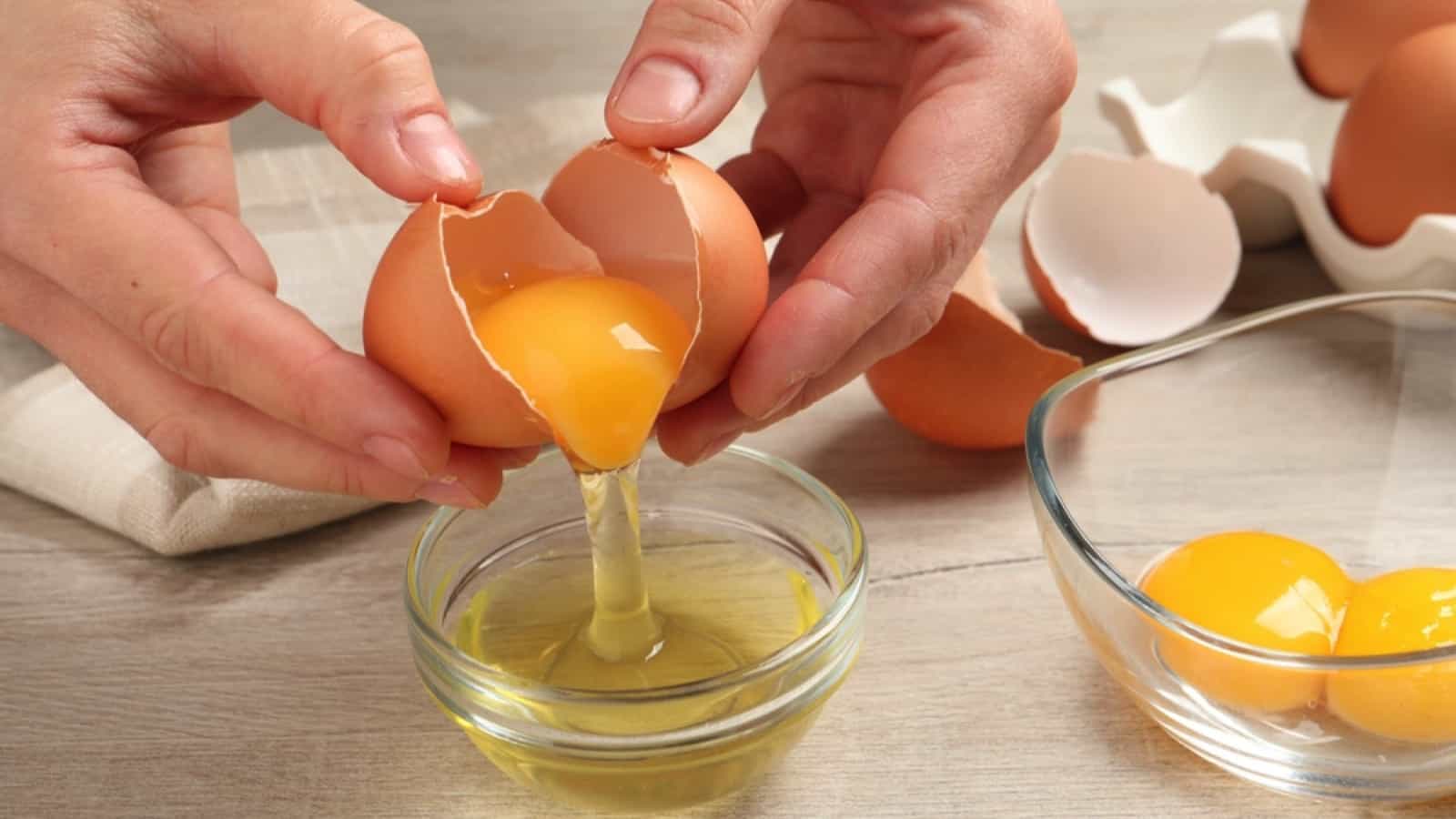 A person is putting eggs into a glass of oil.