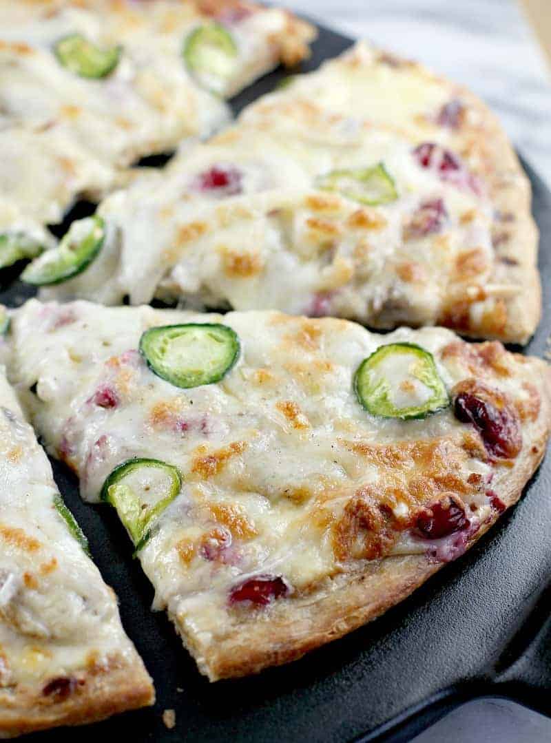 Cranberry jalapeno pizza with ground sausage in a cast iron skillet.