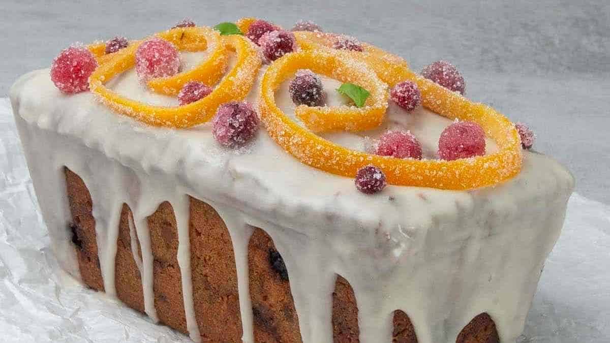 A cake with oranges and cranberries on top.