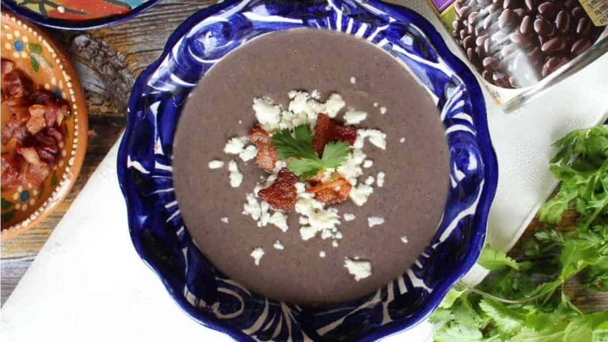 A bowl of black bean soup on a table.