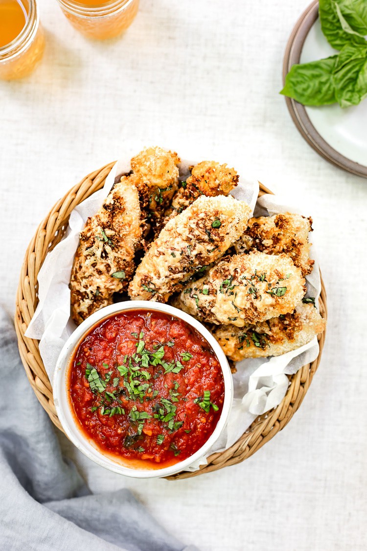 Delicious chicken fingers in a basket with tangy tomato sauce, perfect for anyone looking for new chicken tender recipes.