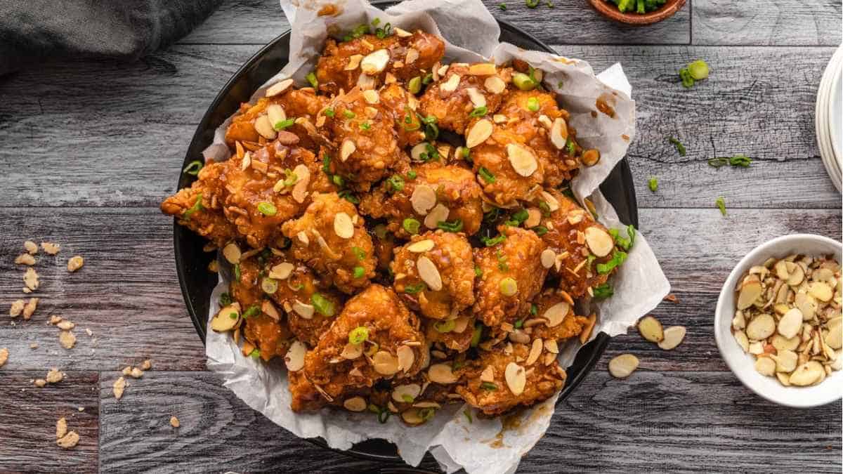 Fried chicken wings with almonds and nuts on a wooden table.
