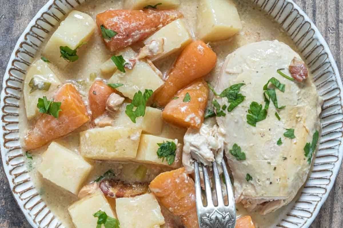 A plate with chicken, potatoes, carrots and a fork.