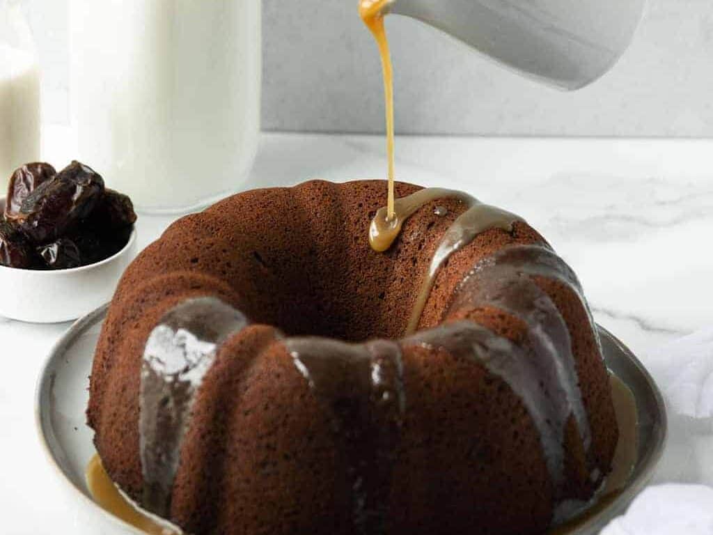 A bundt cake is being drizzled with caramel sauce.
