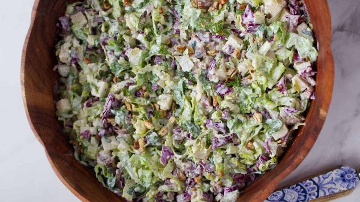A bowl of salad with lettuce and walnuts.