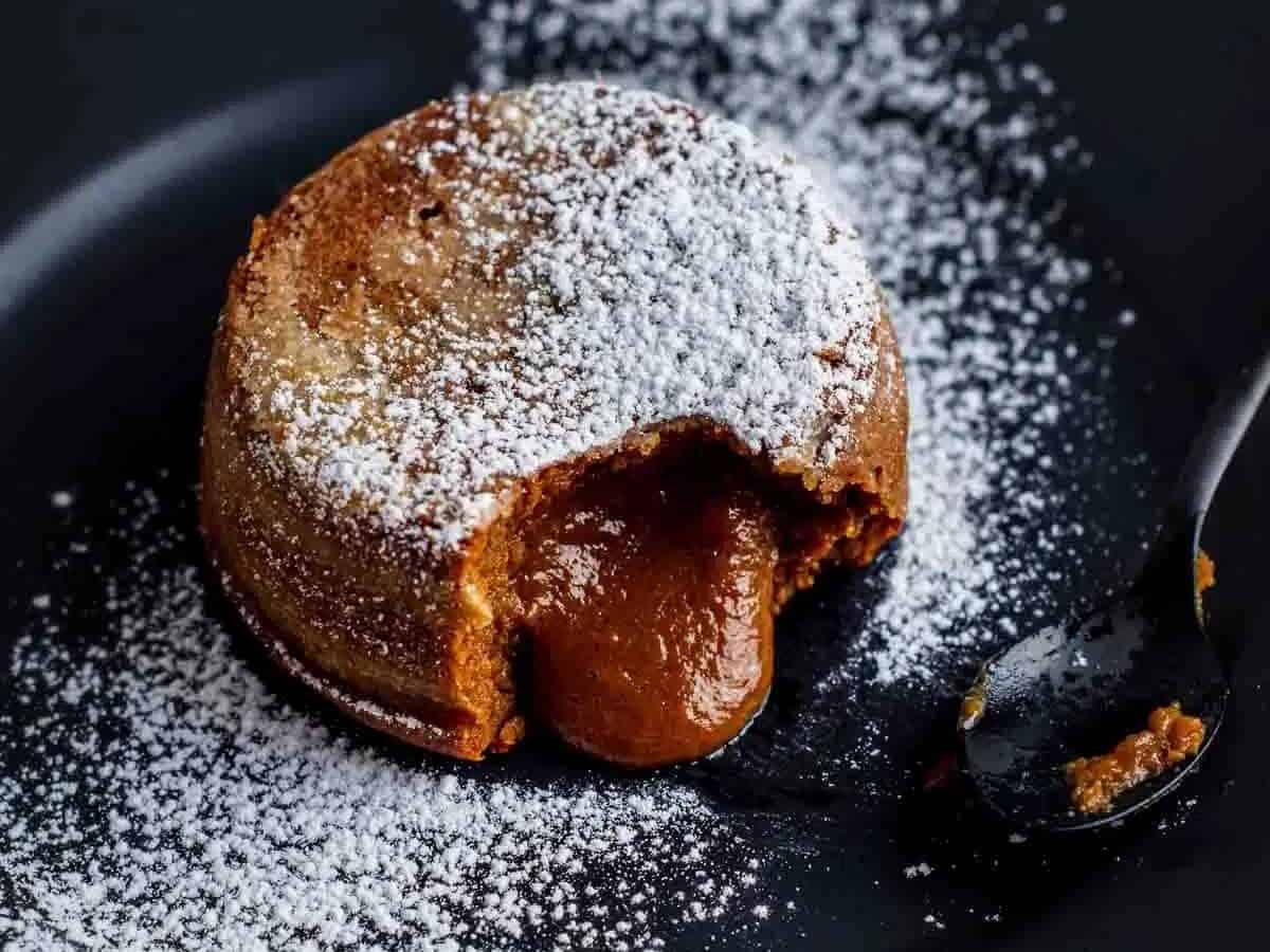 A dessert on a black plate with powdered sugar.
