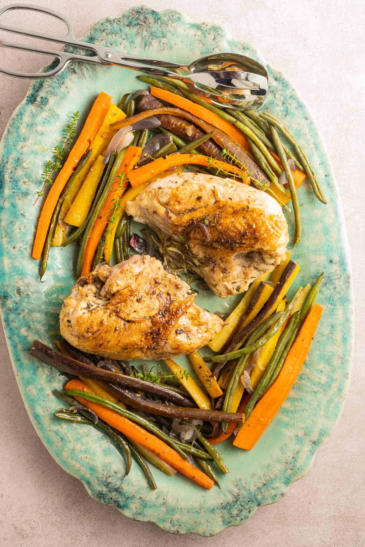 Delicious bone-in chicken breast roasted with a medley of seasonal vegetables on a plate.