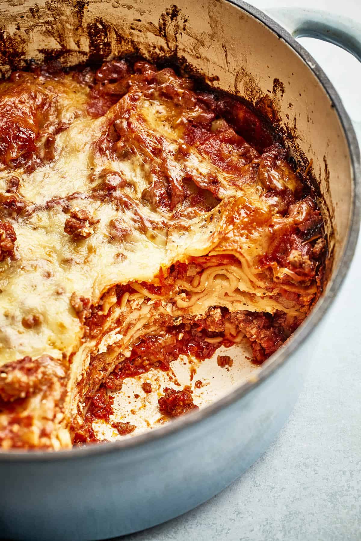 Savory lasagna in a pan layered with ground sausage, topped with melted cheese.