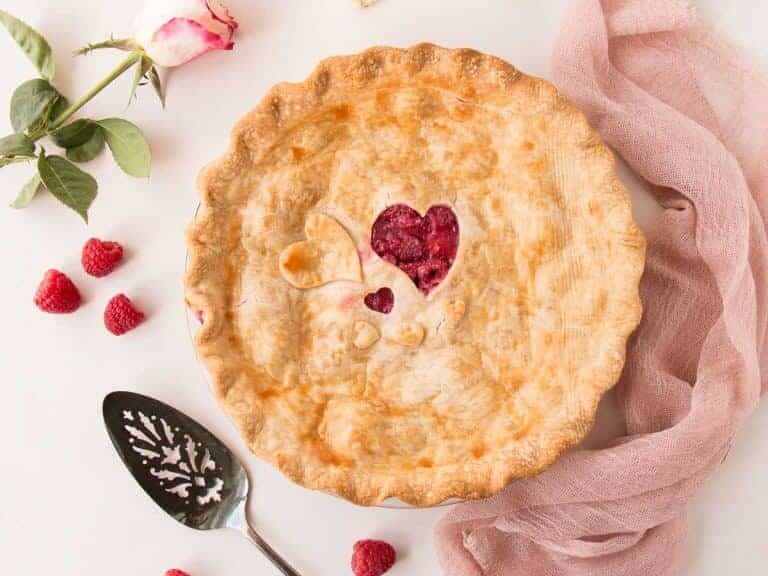 A pie with raspberries and a spoon next to it.