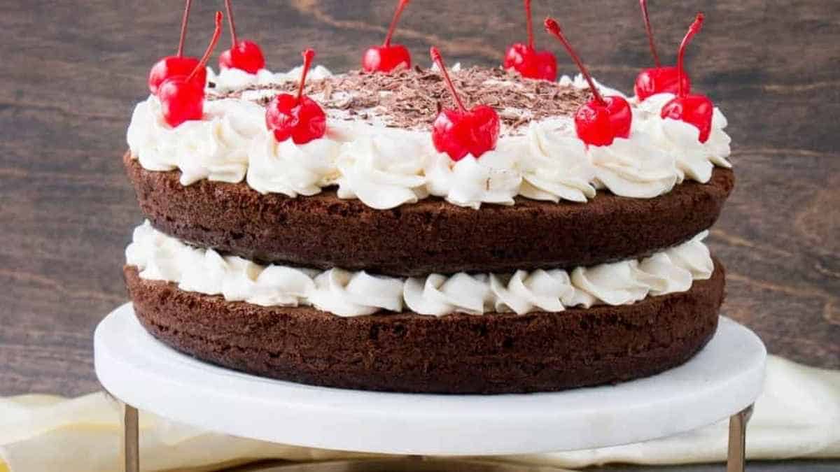A chocolate cake with whipped cream and cherries on top.