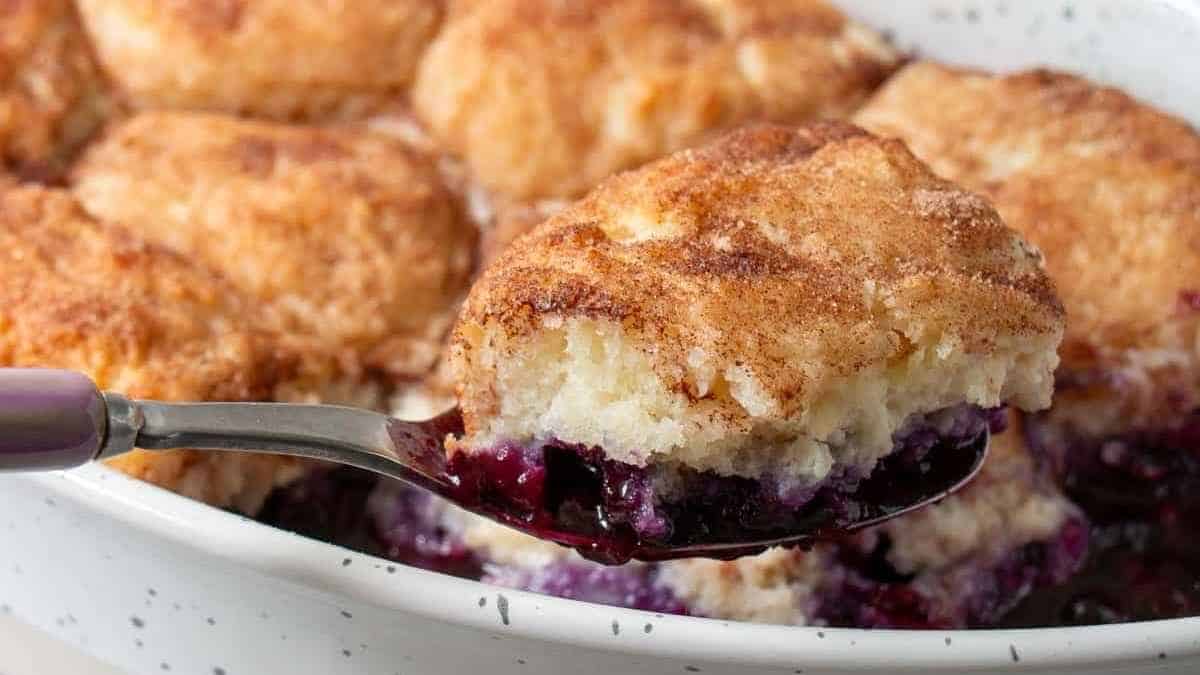 A spoonful of blueberry cobbler in a white dish.