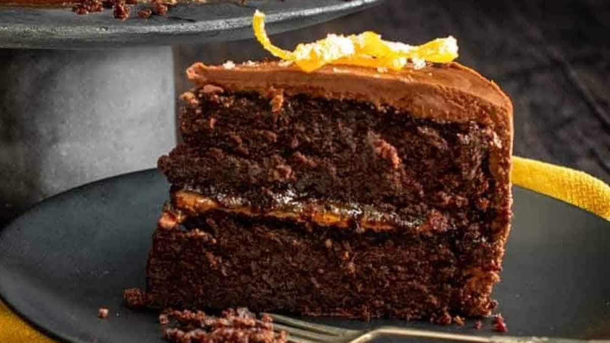 A slice of chocolate cake with orange zest on a plate.