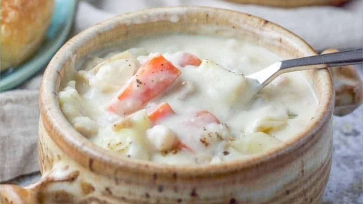 A bowl of chowder with a spoon in it.