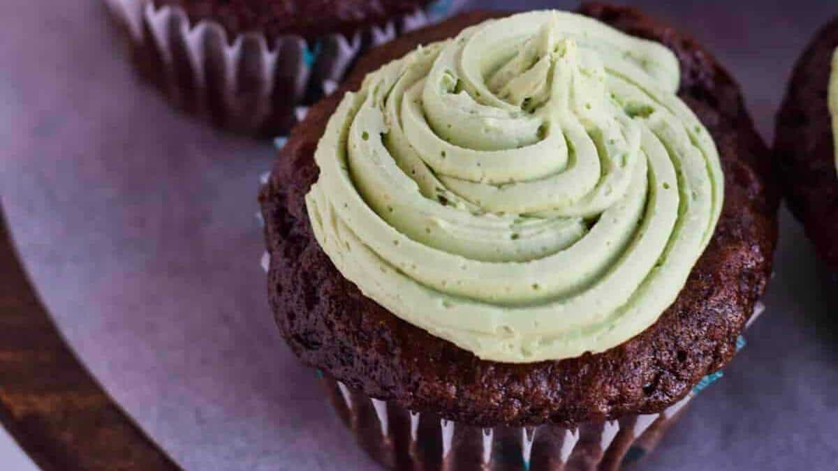 Chocolate cupcakes with green frosting on a plate.