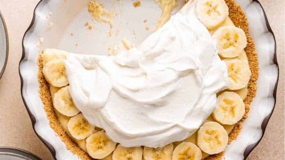 A slice of banana pie with whipped cream on top.