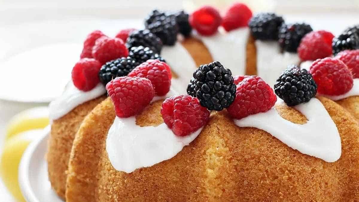 A bundt cake topped with berries and icing.