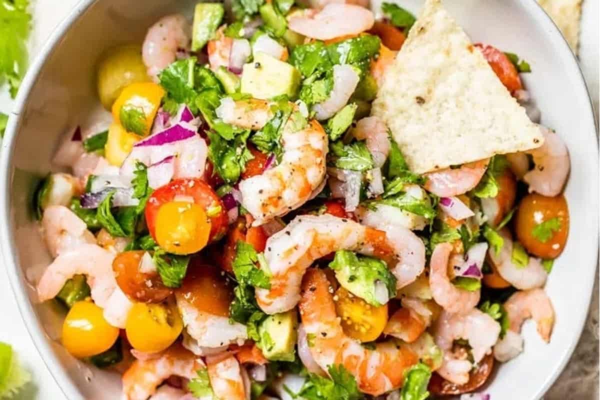 Shrimp salad in a white bowl with tortilla chips.