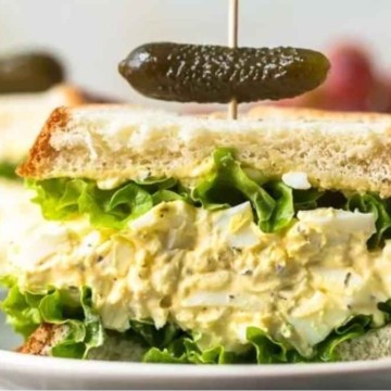 Egg salad sandwich with grapes and pickles.