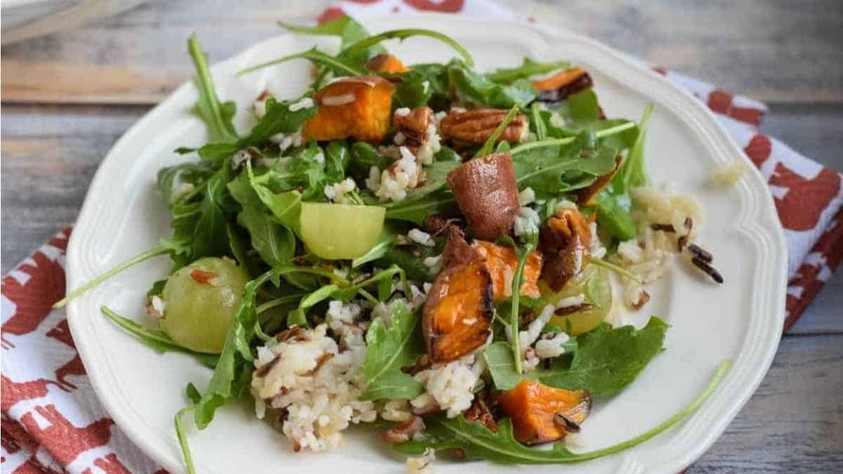 A plate of a salad with carrots, arugula and rice.