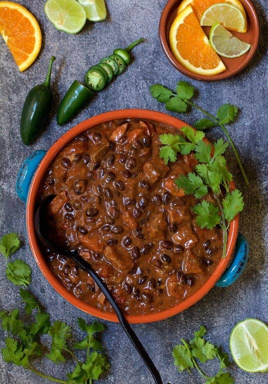 Black bean chili with chuck steak in a bowl with oranges and limes.