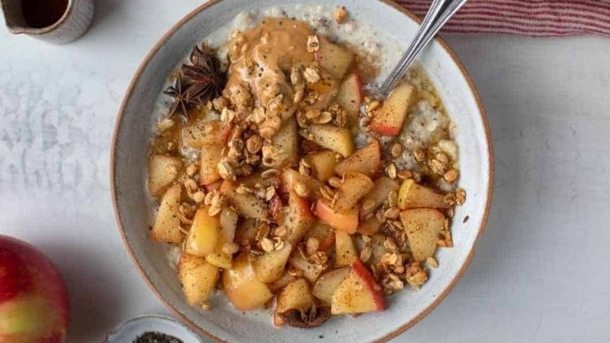 A bowl of oatmeal with apples and peanut butter.
