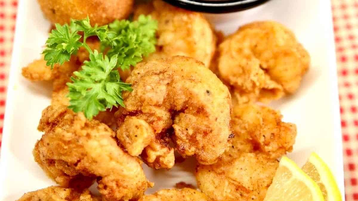 Fried shrimp with dipping sauce on a white plate.