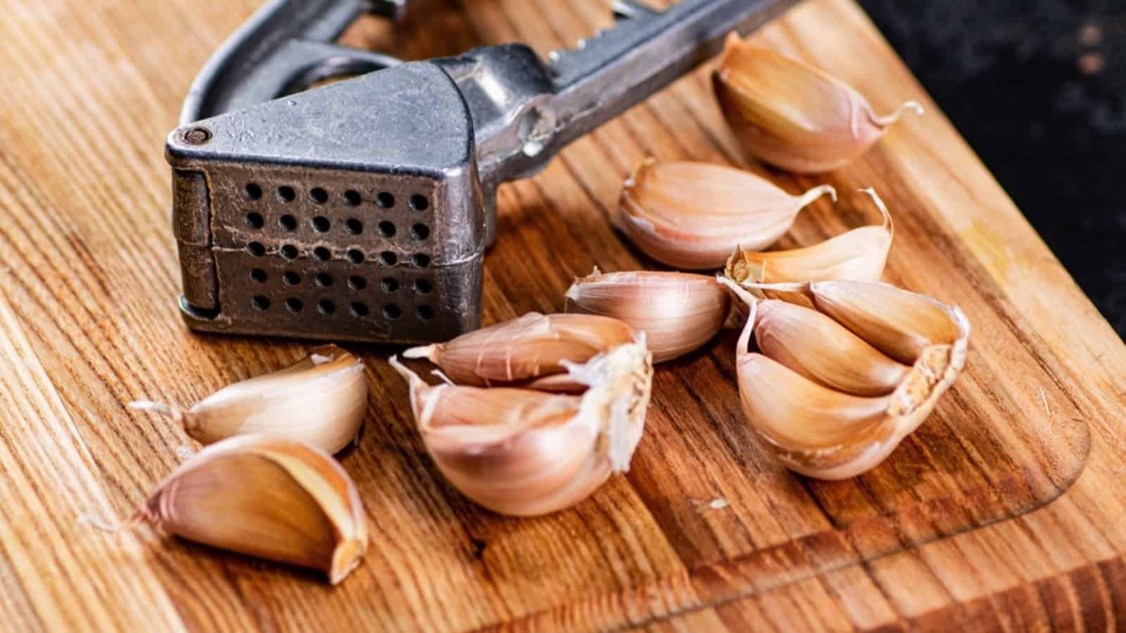 Garlic and garlic grater on a wooden cutting board.
