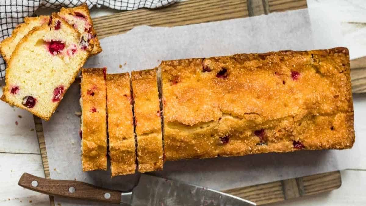 A slice of cranberry bread on a cutting board.