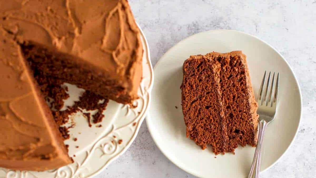 A slice of chocolate cake on a plate with a fork.