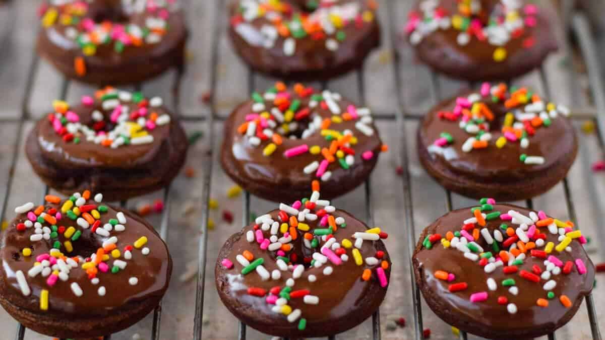 Chocolate donuts with sprinkles on a cooling rack.