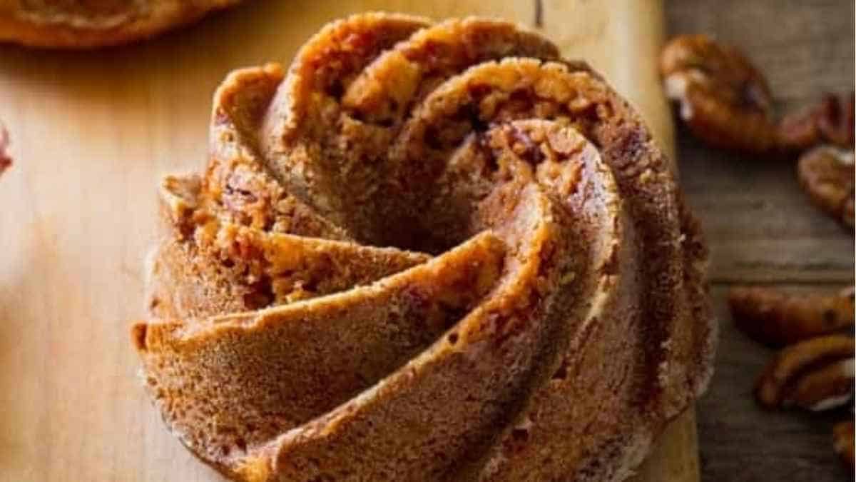 A bundt cake with pecans on a cutting board.