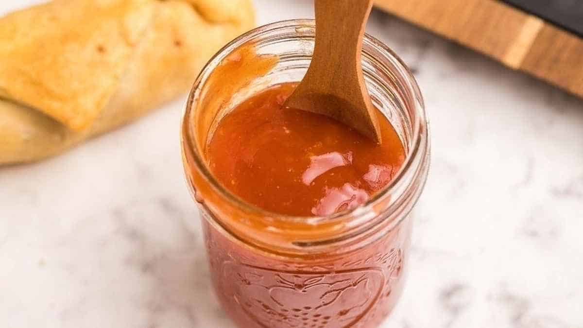 Homemade tomato sauce in a jar with a wooden spoon.