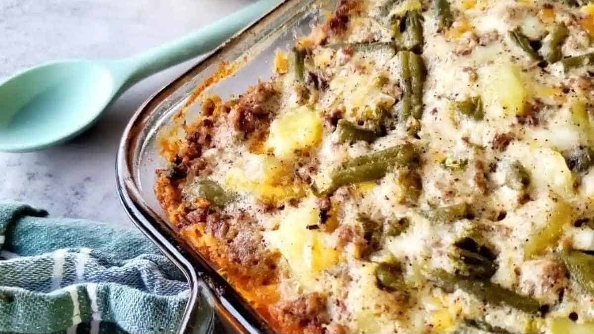A casserole dish with green beans and meat in it.