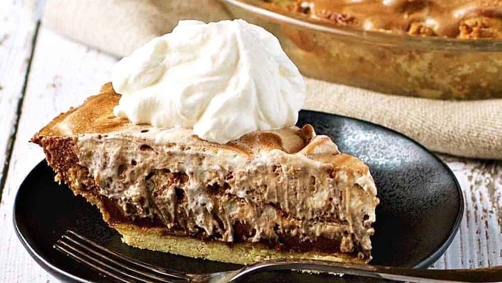 A slice of peanut butter pie on a plate with whipped cream.