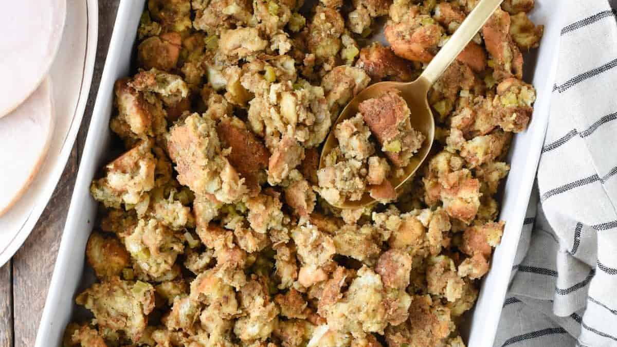 Thanksgiving stuffing in a white dish with green beans and gravy.