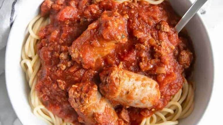 Spaghetti and meatballs in a white bowl.