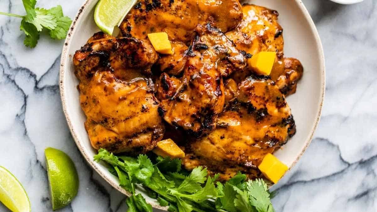 Grilled chicken on a white plate with lime wedges.