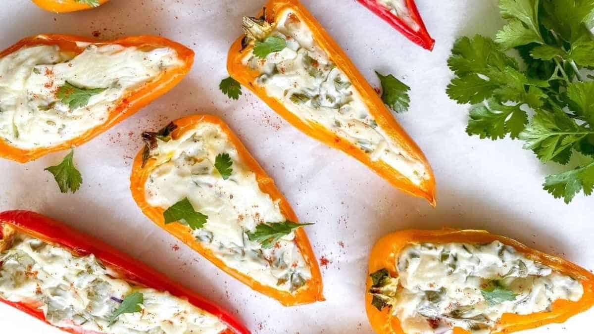 Stuffed peppers with cheese and parsley on a white plate.