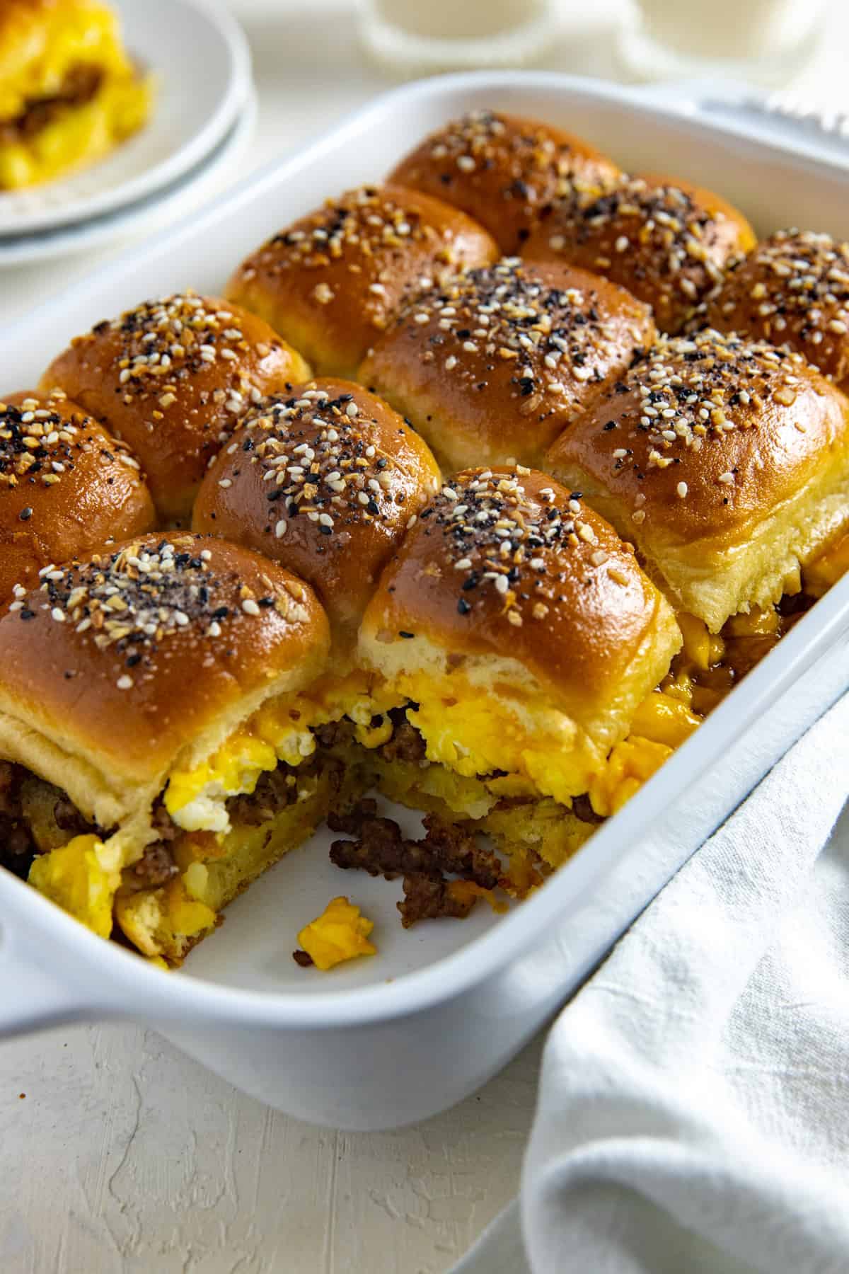 Ground sausage breakfast sliders in a white dish with sesame seeds.