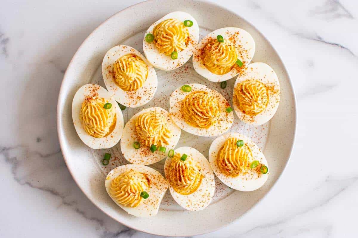 Deviled eggs on a white plate with green onions.
