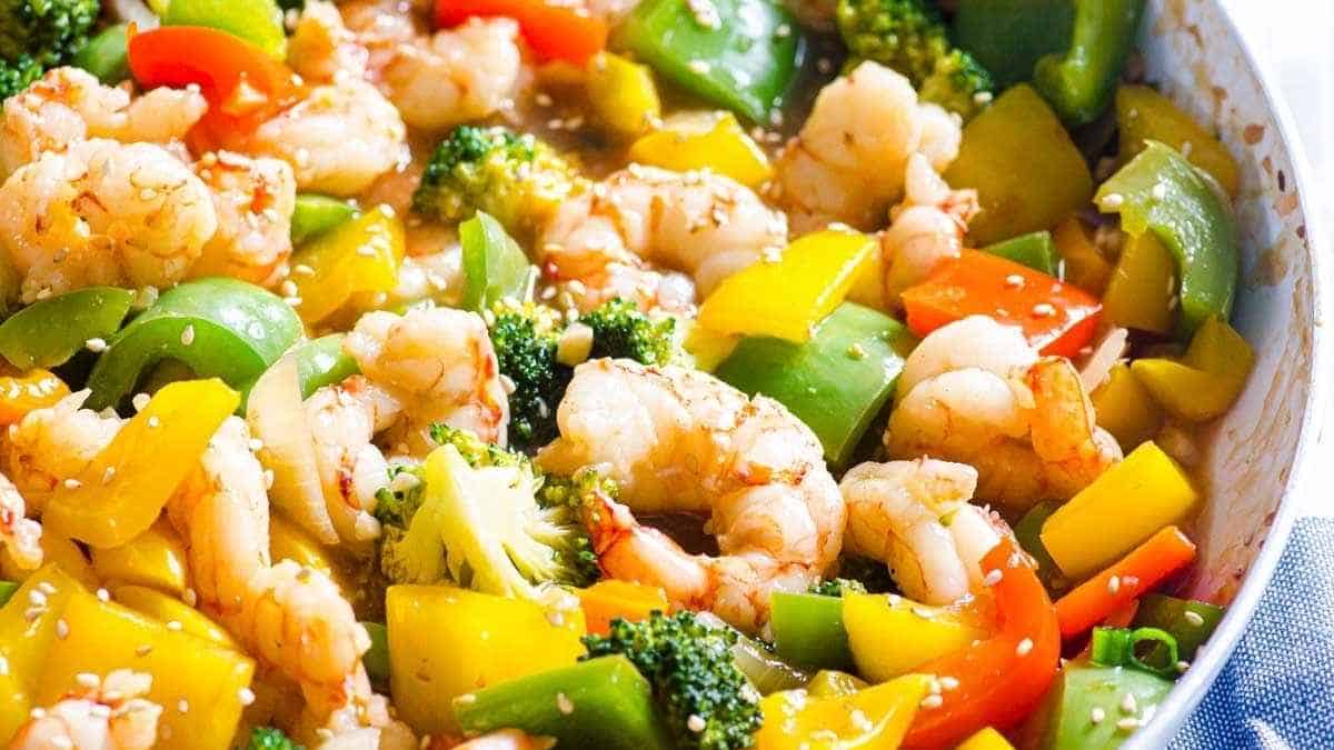 A pan full of vegetables and shrimp in a skillet.