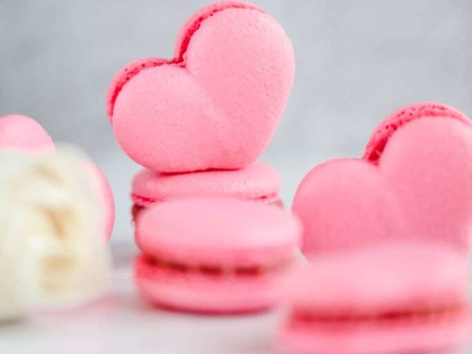 Pink heart macarons on a white surface.