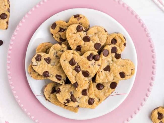 Heart shaped chocolate chip cookies on a pink plate.